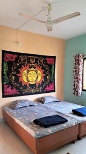 Ce lit se trouve dans un dortoir doté d'une tapisserie murale. dans l'établissement Bageecha B&B-Jal, à Alibaug