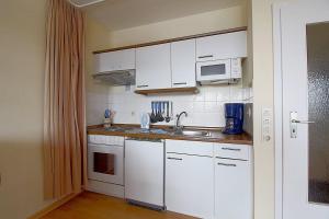 uma cozinha com armários brancos, um lavatório e um micro-ondas em Apartment 426 em Hohegeiß