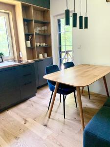 cocina con mesa de madera y sillas azules en Olimian Oasis Village Lipa 107, en Podčetrtek