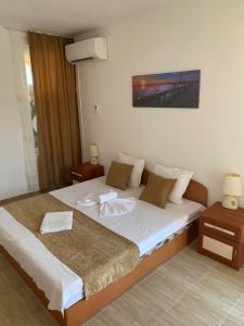 a bedroom with a large bed and two night stands at Хотел CANAVAN'S - beach in 2 minutes, free parking and WiFi in Ravda