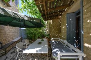 eine Terrasse mit einem Tisch, Stühlen und einem Sonnenschirm in der Unterkunft Kandinella in Lambiní