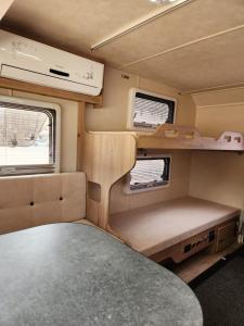 un interior de una caravana con una mesa y dos ventanas en Muscat Caravans, en Barka