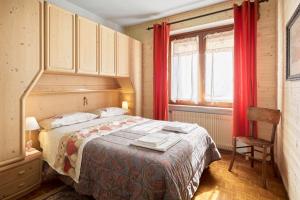 1 dormitorio con 1 cama y una ventana con cortinas rojas en Casa ai Lali, en Forno di Zoldo