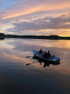 dwoje ludzi w łodzi na jeziorze o zachodzie słońca w obiekcie Pušų gaudyklė w mieście Ginučiai