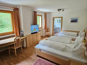 a bedroom with two beds and a desk with a tv at Garni Olympia in Solda