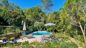 una piscina en un jardín con sillas y sombrilla en Azur Blue Villa; Rural Peace with private pool, en Peymeinade