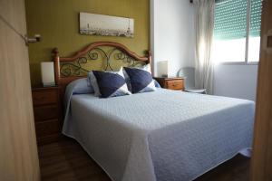 a bedroom with a white bed with blue pillows at Mediterraneo in Faro de Cullera