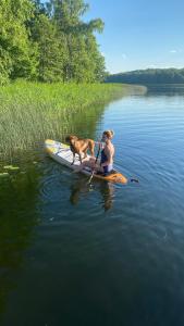 a woman and a dog on a kayak in the water at Pušų gaudyklė in Ginučiai