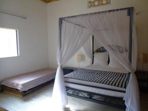 Mbodiène的住宿－WouroBa，一间卧室配有两张床和一张天蓬床。