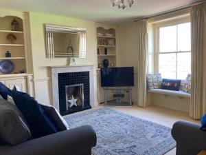 uma sala de estar com lareira e televisão em Harbourside Cottage em Weymouth