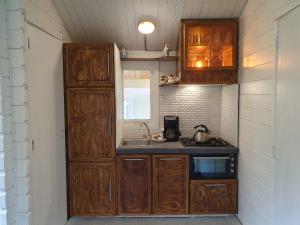 een kleine keuken met houten kasten en een wastafel bij het Uylennest, uniek en goedkoop! in Hem