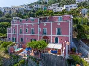 une maison rose sur le flanc d'une colline dans l'établissement Palazzo Rocco - Golden Suite - Praiano - Amalfi Coast, à Praiano