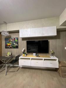 a kitchen with white cabinets and a flat screen tv at Luxury Suite in Araneta in Manila