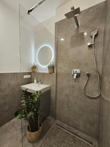 une salle de bain avec une douche avec un lavabo et un miroir dans l'établissement 2 room Apartment, new building, Bosákova street, 49, à Bratislava