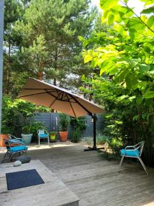 een patio met 2 stoelen en een parasol bij Su terasa jaukus apartamentas, tik vienas in Palanga