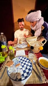 two men and a woman sitting at a table at Exceptional Luxury Camp in Merzouga