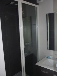 W łazience znajduje się szklana kabina prysznicowa i umywalka. w obiekcie Hotel De La Plage w mieście Quiberville