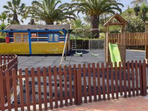 um parque infantil atrás de uma cerca com um parque infantil em Stunning Villa with Pool & View near beach em Budens