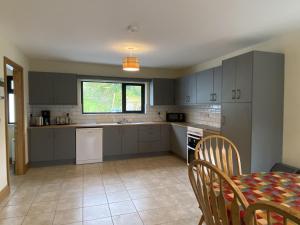 a kitchen with gray cabinets and a table and a dining room at Cottage 442 - Oughterard in Oughterard