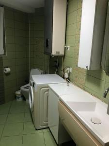 a bathroom with a washer and a sink and a toilet at Bube Apartment in Skopje