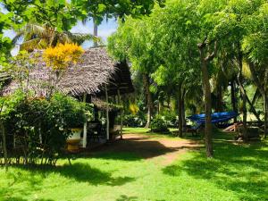 a house with a straw roof and some trees at Lake view cabana Paradise & Villa in Tangalle