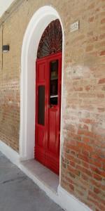 a red door in the corner of a brick wall at Casa Antica a 10 metri dalla Spiaggia con giardino interno in Porto Recanati