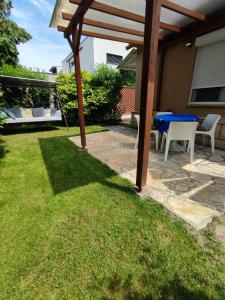 a patio with a table and chairs under a wooden pergola at Apartman Valentin in Siófok