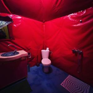 a red bathroom with a toilet and a sink at Exceptional Luxury Camp in Merzouga
