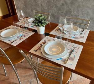 un tavolo in legno con piatti e bicchieri da vino sopra di Attico in Piazza Matteotti a Desenzano del Garda