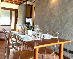 un tavolo in legno con sedie, piatti e bicchieri da vino di Attico in Piazza Matteotti a Desenzano del Garda
