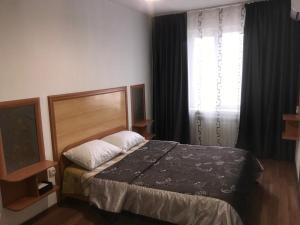 1 dormitorio con cama y ventana en Apartments on Koktem 1, en Almaty