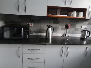 a kitchen with a black counter top with a microwave at Sami BnB - Apt 04 Makongo after Mlimani City in Dar es Salaam