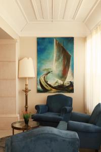 a living room with a blue couch and a painting of a boat at Hotel Joao Padeiro in Aveiro