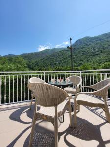 three chairs and a table on a balcony with mountains at Apartments Lalević in Donji Morinj