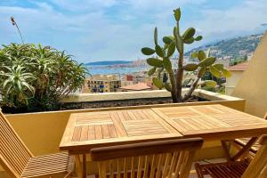 a wooden table on a balcony with a cactus at Mansfield vue carte Postale Terrasse Piscine 2 in Menton