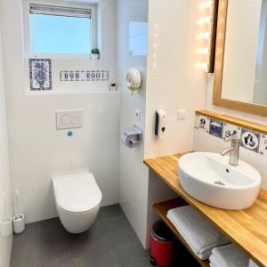 bagno con servizi igienici bianchi e lavandino di Rooi Bij de Knoptoren B&B a Sint-Oedenrode