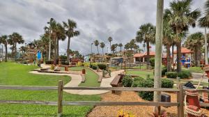 a park with a playground with palm trees at Driftwood Beach Motel in Ormond Beach