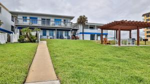 a walkway in front of a building with a grass field at Driftwood Beach Motel in Ormond Beach +31 photos