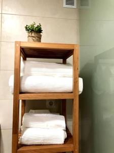 a wooden shelf with folded towels and a plant on it at En Patio sevillano Alameda-Isla Magica in Seville