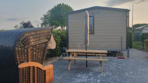 ein Picknicktisch mit einer Bank neben einem winzigen Haus in der Unterkunft Campingland Ostsee - Mobilheim 74Strandzauber NEU! in Schashagen