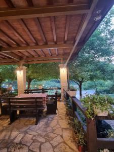 un patio con pergolato in legno, tavolo e panche di Guesthouse Alberti Llogara a Shalë