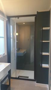 La salle de bains est pourvue d'une douche en verre et d'un lavabo. dans l'établissement Campingland Ostsee - Mobilheim 74Strandzauber NEU!, à Schashagen