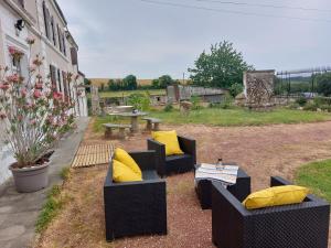 a patio with two couches and a table with yellow pillows at Maison Rouge in Saint-Jean-dʼAngély