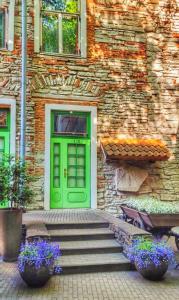 a green door of a stone building with stairs and flowers at St.Olav Hotel in Tallinn