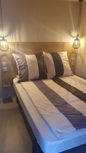 Una cama con dos luces encima. en Campingland Ostsee - Mobilheim 74Strandzauber NEU!, en Schashagen