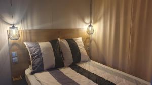 a bedroom with a bed with two lights on it at Campingland Ostsee - Mobilheim 74Strandzauber NEU! in Schashagen