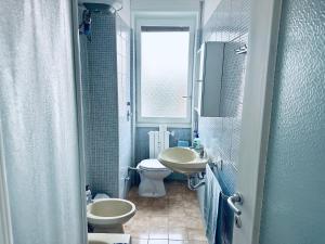 a bathroom with two sinks and a toilet and a window at Blue Milano in Milan