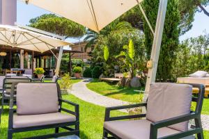 un groupe de chaises sous un parasol dans une cour dans l'établissement Hotel Isola Sacra Rome Airport, à Fiumicino