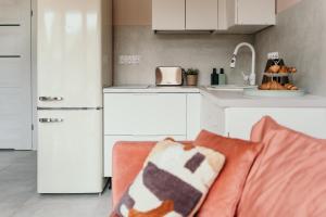 a kitchen with white cabinets and a couch in a room at Domek Discovery Mazury in Mrągowo