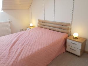 a bedroom with a pink bed with two lights on it at Ferienhaus im Kirschbäumchen in Osburg